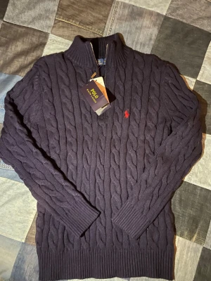 Mörkblå kabelstickad tröja Polo Ralph Lauren -  Mörkblå tröja från Polo Ralph Lauren med halv dragkedja. Priset kan diskuteras lite. 