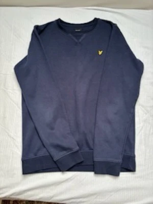 Mörkblå sweatshirt från Lyle & Scott - Mörkblå sweatshirt från Lyle & Scott med klassisk rund halsringning och den ikoniska gula logon broderad på bröstet. Tröjan har långa ärmar och ribbade muddar vid ärmslut och nederkant. Perfekt för en avslappnad och stilren look. Strlk S 