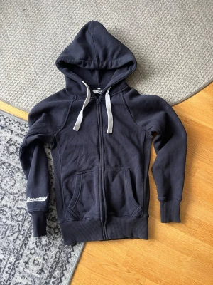 Russemerch zip hoodie mörkblå - Mörkblå hoodie med vita snören i huvan. 