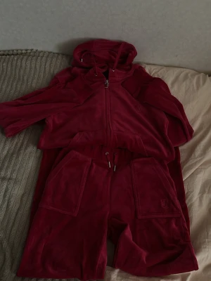 Rött Juicy set❣️ - Mysigt rött juicy set!❣️Haft båda i ca 2 år men använt de nästan 2-3 gånger! Säljer de då jag inte använder dem alls! Byxorna är i st XS och koftan i M❣️ 
