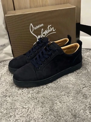 Mörkblå sneakers Christian Louboutin - Snygga mörkblå sneakers från Christian Louboutin i mocka med klassisk röd sula och svarta snören. Insidan är beige och skon har en stilren, låg profil som passar till många olika outfits. Ikonisk logga på sulan för extra lyxig känsla. Jätte bra skick, för dig som gillar stil och är grish🤩 hör av er vid intresse och lägg era bud 