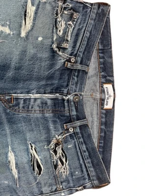 Blå slitna jeans från Stone Island - Säljer ett par blå jeans från Stone Island med tydliga slitningar och hål för en riktigt edgy look. Jeansen har raka ben, klassisk femficksmodell och är gjorda i denim. Perfekta för dig som vill sticka ut med en rå stil. Det står att de är W31 men kan sitta bra på folk som normalt sett har smalare storlekar. Hör av er för precisa måtten!