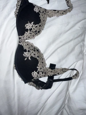 Intimissimi Bh - Jättefin svart BH med vackra vita spetsdetaljer. Storlek 75B. En superfin och smickrande modell som sitter bekvämt och ger bra stöd. Perfekt både till vardags och till speciella tillfällen. Finns små slitningar som ej syns! 