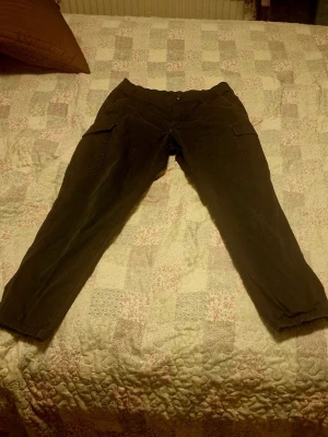 Svarta carbobyxor från Uniqlo - Säljer ett par svarta byxor från Uniqlo med raka ben och praktiska sidfickor. Byxorna är tillverkade i bomull med lite elastan för extra komfort. Perfekta för dig som gillar en avslappnad men ändå stilren look.