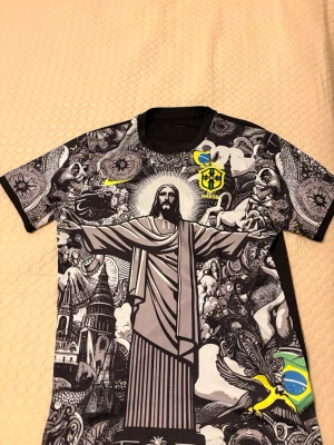 Brasil t-shirt med grafiskt tryck - Brasilien T-shirt – Storlek XL – Ny – 400 kr  Säljer en helt ny och oanvänd T-shirt i storlek XL. Riktigt snygg och unik design med Kristusstatyn och Brasilien-tema samt CBF-märke.  • Storlek: XL • Skick: Ny  • Färg: Svart med tryck • Pris: 400 kr  Perfekt för dig som gillar Brasilien, fotboll eller vill ha en stilren och annorlunda tröja.  Hör av dig vid intresse! 😊