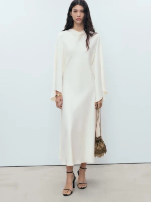 Ljus långklänning med vida ärmar - Elegant ljus långklänning med rund hals och vida, långa ärmar. Klänningen har en rak och flowy passform och är tillverkad i satin. Använd 1 gång