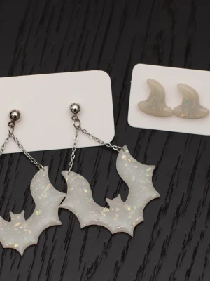 Handgjorda örhängen i polymerlera och stift i rostfritt stål halloween fladdermus bat glitter offwhite  - Handgjorda örhängen i polymerlera och stift i rostfritt stål.  Självklart nya och oanvända. Storlek: Fladdermöss 4x6cm. Häxhattarna (stiftörhängen) 1,5x1,5cm. De är lite mer vita än på bilderna.  Färgerna kan variera beroende på skärminställningar.
