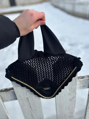 Svart huva från Equestrian Stockholm - Säljer en svart huva från Equestrian Stockholm med guldfärgad kant och nätmönster. Huvan har mjuka öron i tyg och en liten metallbricka med logga framtill. Perfekt för häst och ridning. Str ponny
