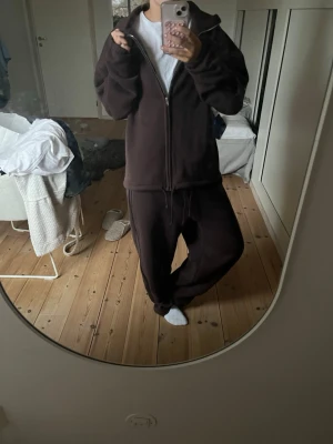 Brunt mjukissett från Gina Tricot - Ett mörkbrunt mjukissett från Gina Tricot med avslappnad passform och byxorna har dragsko i midjan. Tillverkade i mjukt och skönt material som passar perfekt för chill dagar.