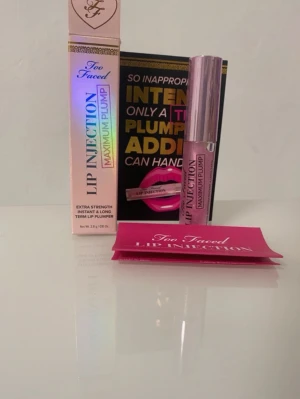 Too Faced Lip Injection Maximum Plump - Läppglans från Too Faced i nyansen Maximum Plump. Kommer i en genomskinlig tub med rosa ton och silvrigt lock. Ger extra volym och glans till läpparna. Förpackningen är rosa med holografiska detaljer och tydlig logga.
