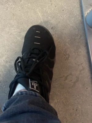 Svarta Nike sneakers vapormax - Svarta vapormax sneakers klassisk design och meshdetaljer för extra andningsförmåga. Skorna har svarta snören, diskreta vita detaljer och en sportig vibe. Perfekta för dig som gillar streetstyle och vill ha bekväma skor till vardags.