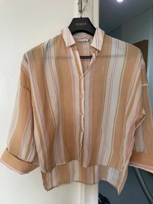 Stockholm  Lm vit randig skjorta - Säljer Stocholm lm .en luftig skjorta från Pieces i beige, vitt och ljusrosa randigt mönster. Skjortan har knappar framtill, krage och trekvartsärmar med knapp vid ärmslut. Storlek är ex men som S fungerar också 