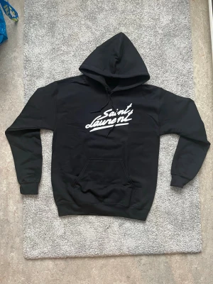Svart Saint Laurent Hoodie - OBS! Ej äkta} Endast använd en gång. Tröjan har inga lappar. Mått: längd-59cm bredd-48cm | Fraktas inom 15h 🚚💨📦❤️