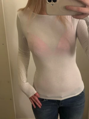 Vit långärmad tight topp - Säljer en vit, långärmad och tight topp med rund hals. Toppen är tunn och har en enkel, stilren design som sitter figurnära. Perfekt att styla med jeans eller kjol för en clean look.