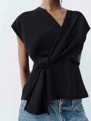 Svart zara topp  - Snygg svart topp med knyt i midjan och v-ringad hals. Toppen har korta ärmar och materialet känns mjukt och har ett fint fall. 