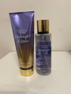 Victoria's Secret Midnight Bloom set - Säljer ett set med Victoria's Secret Midnight Bloom, innehållande en body mist och en lotion. Båda har en snygg lila och guldig design med eleganta detaljer. Doften är blommig och fräsch, perfekt för dig som gillar en feminin och modern parfym.