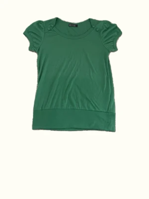 Grön topp med ”puffärmar” - Snygg grön topp med rund halsringning och korta puffärmar med knappdetaljer vid axlarna. Bred ribbad kant nedtill ger en schysst passform. Perfekt att styla med jeans eller kjol för en fräsch look.