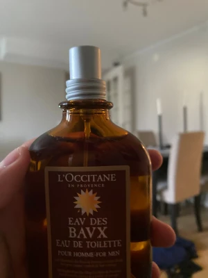 L'Occitane Eau des Baux EdT 100ml - L'Occitane Eau des Baux Eau de Toilette för män i en brun glasflaska med silverfärgad spraykork. Flaskan rymmer 100 ml och har en stilren, maskulin design med etikett i brunt och guld. Perfekt för dig som gillar eleganta och klassiska dofter. Paket och kvitto finns ej med.