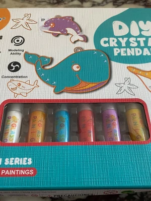 DIY Crystal Pendant Ocean Series - Säljer ett DIY Crystal Pendant kit från Ocean Series med färgglada målarfärger, pärlor och verktyg. Setet innehåller sex färgtuber, pärlkedjor, transparent tråd och pincett. Perfekt för att skapa egna hängsmycken med havstema som valar och fiskar.