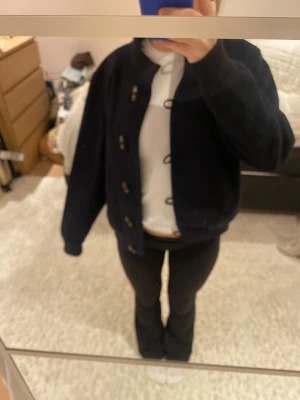 Mörkblå teddyjacka med knappar - Teddyjacka i mörkblå färg med rund hals och stora knappar framtill. Jackan har en loose passform och är långärmad.