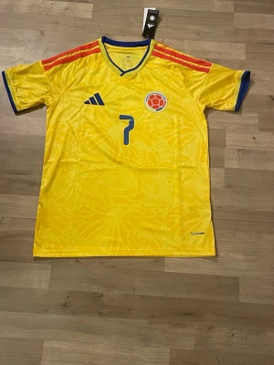 Colombia matchtröja Luis Diaz #7 storlek S - Gul Colombia matchtröja från Adidas med blå detaljer och röda ränder på axlarna. Nummer 7 och Luis Diaz tryckt på ryggen. Storlek s