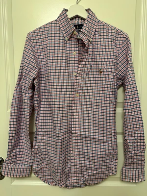 Skjorta från Ralph Lauren - Snygg rutig skjorta från Ralph Lauren i rosa, blått och vitt. Klassisk button-down krage, långärmad och med broderad logga på bröstet. Skjortan är i bomull och har en slim passform. Perfekt för en stilren look. Sitter som S/M