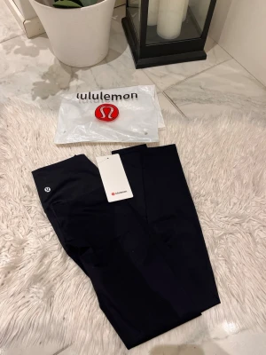 Svarta leggings från Lululemon - Snygga svarta leggings från Lululemon med hög midja och stretchigt material. Diskret logga på benet och klassisk tight passform. Perfekta för träning eller chill. Kommer med originalpåse och tag kvar.
