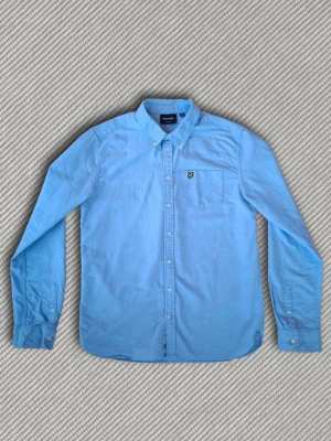 Lyle & Scott skjorta - Säljer en ljusblå skjorta från Lyle & Scott. Modellen är 173cm lång och skjortan sitter ungefär som en storlek 170cm. Riktigt snygg skjorta i mcyket bra skick, som passar till både vardag och finare tillfällen. Ifall du har fler frågor skriv gärna!👍