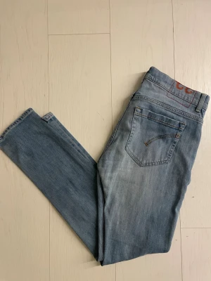 Dondups  - Säljer ett par ljusblå skinny jeans från Lee med klassisk femficksdesign och diskreta slitningar. Jeansen har raka ben och är tillverkade i mjuk denim med en liten logga på bakfickan. Perfekta för en avslappnad och trendig look.