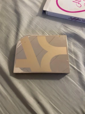 Highlighterpalett från kicks  - Säljer en highlighterpalett från kicks med fyra skimrande nyanser i champagne, guld, brons och ljusrosa. Paletten har en stilren beige och guldfärgad design med spegel i locket. Perfekt för att skapa glow och highlighta ansiktet.