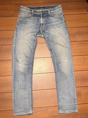Vintage Nudie jeans - Ett par feta Vintage Nudie jeans i en ljusblå urtvättad naturlig wash efter många års användning. Storlek 33/32.  Modellen heter Thinn Finn och är en slim-straight passform med organisk bomull.                                                            2 Små lagningar mellan benen. Syns inte när dem används. Annars fel fria.