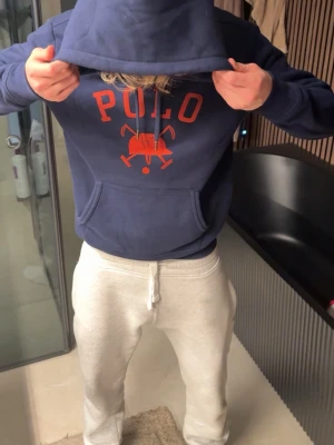 Säljer alla dessa tre för totalt 1200 kr  - Mörkblå hoodie från Polo Ralph Lauren med stor röd POLO-logga och polospel-tryck på bröstet. Klassisk känguruficka framtill och justerbar huva. Perfekt för en avslappnad och sportig stil.