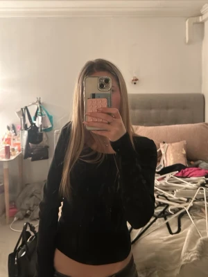 Svart långärmad topp - Snygg svart långärmad topp med figurnära passform. Perfekt att styla med jeans eller kjol för en trendig look. Enkel och stilren design som passar till många olika outfits.