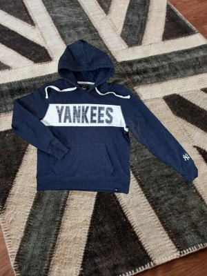 Vintage Yankees hoodie med huva - Tjena! Mörkblå Vintage hoodie från Yankees med stor vit logga över bröstet och vita detaljer på axlarna. Klassisk känguruficka framtill och broderad Yankees-logga på ärmen. Tröjan är i riktigt bra skick! För mer info är de bara o skriva!