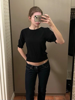 Svart topp med puffärm - Säljer en jättefin svart topp med puffärm och rund halsringning. Toppen har resår i midjan. Perfekt till jeans eller kjol för en stilren look.