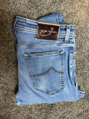 Blå jeans från Jacob Cohen - Snygga blå jeans från Jacob Cohen med klassisk femficksdesign och kontrastsömmar. Jeansen har en normal passform och är tillverkade i mjuk bomull med en skön stretch. Perfekta för dig som gillar en enkel men stilren look.