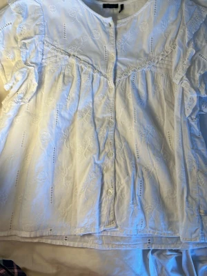 Vit broderad blus - Söt vit blus från IKKS med broderade blommor och spetsdetaljer. Jättesöt till sommaren. Storlek 160 men passar xs/s