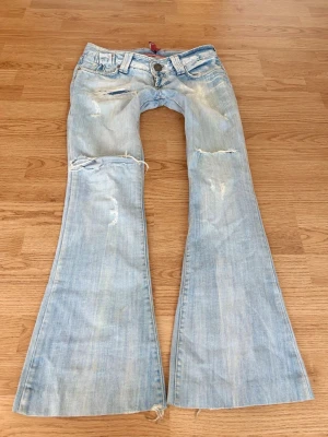 Vintage superlågmidjade ljusblå slitna bootcut jeans - Såå snygga vintage superlågmidjade ljusblå bootcut jeans med slitna detaljer och hål! ❤️Innebenslängd: 80 cm Midjemått: 39 cm 
