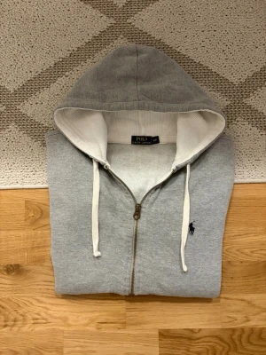 Ljusgrå Polo Ralph Lauren Zip Up Hoodie - Hej!👋  Säljer en ljusgrå zip up hoodie från Polo Ralph Lauren. Den är i mycket fint skick, utan fläckar eller hål.  Storlek: S/P i herrstorlek, 170/92A. Mått skickas privat!✅😀 Skickar snabbt!🚛📦 Hör av er vid frågor!💯