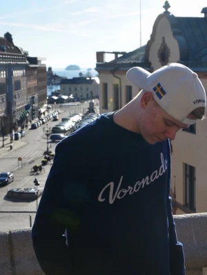 Mörkblå stickad tröja Voronado Atelier - Snygg mörkblå stickad tröja från Voronado med vit broderad logga över bröstet. Tröjan har rund halsringning och långa ärmar. Perfekt för dig som gillar stilrena och klassiska plagg med en modern touch.