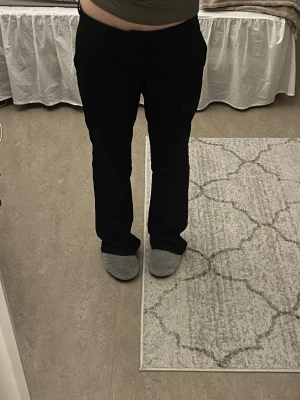 Svarta kostymbyxor - Säljer ett par svarta bootcut kostymbyxor och låg midja. Byxorna har klassisk look och är perfekta till en snygg outfit. Materialet ser ut att vara mjukt och följsamt, troligen polyester eller bomullsblandning. Inga synliga detaljer eller märke. Säljer på grund av att de är för stora på mig. 