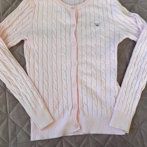 Ljusrosa kabelstickad kofta från Gant - Söt ljusrosa kabelstickad kofta från Gant med rund halsringning och knappar framtill. Bara att skriva vid frågor 💕💕💕