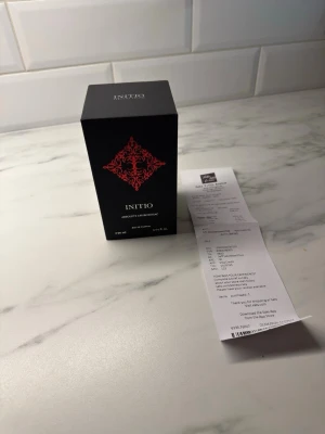 Initio Absolute Aphrodisiac parfym - Initio Absolute Aphrodisiac är en exklusiv parfym i en elegant svart rektangulär förpackning med ett dekorativt rött mönster på framsidan. Flaskan rymmer 90 ml och utstrålar lyx och mystik, perfekt för dig som vill sticka ut med en unik doft.