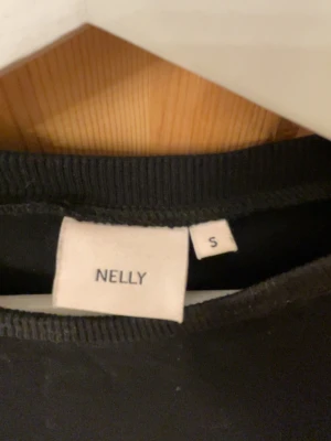 T shirt med rosett bak Nelly  - En svart t shirt från Nelly med korta ärmar. Så fint att man kan knyta där bak till en rosett. T shortsen är i storlek s och är från Nelly. Pris kan även diskuteras💗