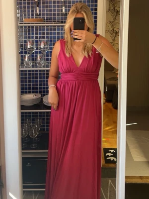 V- ringad balklänning  - Säljer min balklänning i en vinröd/rosa färg med v-ringning. Storlek 36 från Nly eve. Endast använd en gång på ett bröllop. Original förpackning medföljer. Dragkedja under ena armen. Superbra kvalité och jättefint tyg.  Passar till bal, finare tillfällen och även bröllop.  Referens: jag är 178 cm lång och bär vanligtvis M.