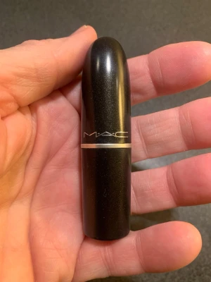 Blått skimrande läppstift från MAC - Snyggt blått / lila läppstift från MAC med skimrande finish. Hylsan är klassiskt rundad och svart med silverdetalj och MAC-logga. Läppstiftet har en djup, metallisk ton som skiftar mellan blått och lila och ger en cool och edgy look.