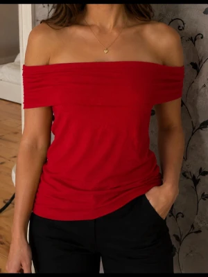 Röd offshoulder topp mindre XL - Trendig röd offshoulder topp med bred kant över axlarna. Toppen är ärmlös och har en smickrande, figurnära passform. Perfekt för dig som vill ha en enkel men snygg look. Tillverkad i mjukt material som känns skönt mot huden. Strl lite mindre mer som strl L. Ingen prislapp i men helt ny och aldrig använd