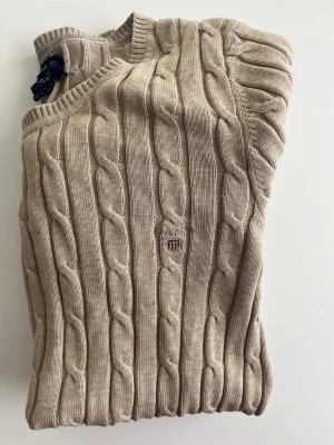 Gant kabelstickad tröja - Tja, säljer denna skitsnygga beigea kabelstickade tröjan från Gant med rund halsringning och diskret logga broderad på bröstet. Passar XS men kanske S också. Är du mellan 160 och 175 kommer denna tröja att förgylla din garderob direkt. Såklart kan du skriva vid frågor eller funderingar🙌