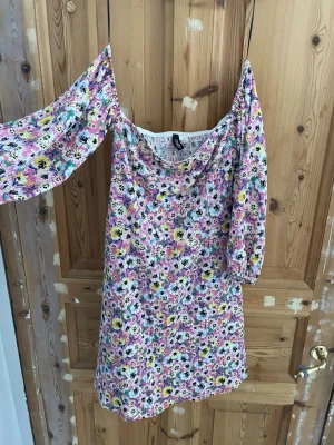Blommig offshoulder klänning H&M - Söt kort blommig klänning från H&M med offshoulder-ärmar. Klänningen har ett färgglatt mönster i rosa, gul, vit och svart samt smockad baksida . Perfekt för varma dagar och har en luftig känsla.