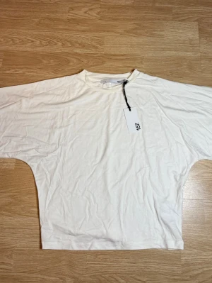 Vit oversized t-shirt från 157 - Säljer en vit oversized t-shirt från 157 med bred passform och rund halsringning. T-shirten har korta ärmar och är gjord i mjuk bomull, i storlek M 